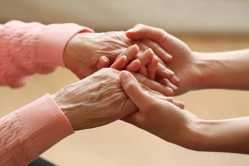 Junge Hand hält die Hand einer älteren Person – Symbol für Vertrauen und Fürsorge im Pflegedienst